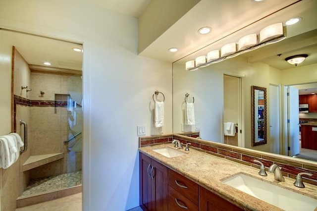 bathroom featuring a shower with door, tasteful backsplash, vanity with extensive cabinet space, and dual sinks