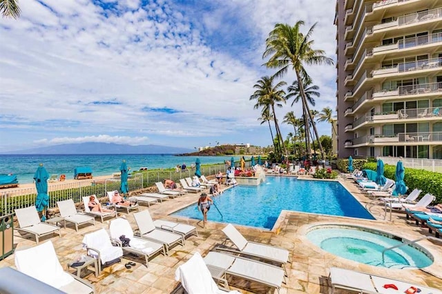 view of pool featuring a patio area, a hot tub, and a water view