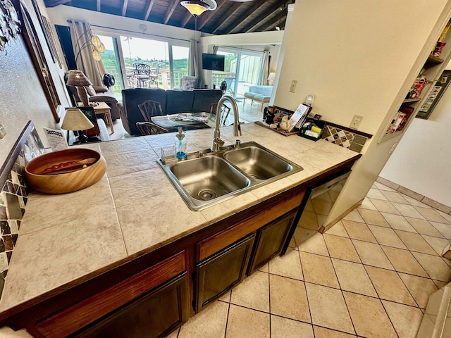 kitchen with lofted ceiling, sink, light tile patterned floors, and dark brown cabinets