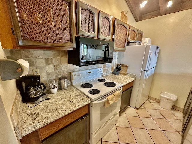 kitchen with light tile patterned flooring, light stone counters, backsplash, and white appliances