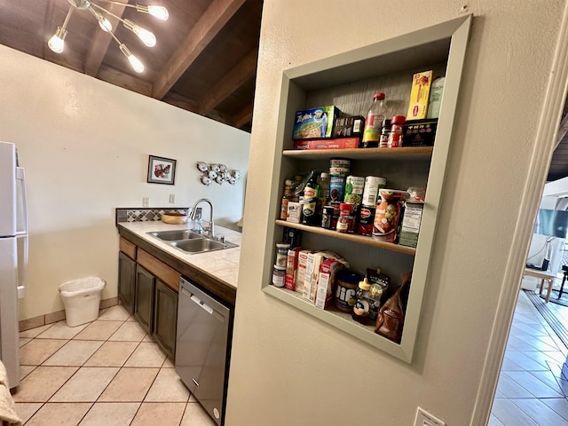 interior space with light tile patterned flooring, sink, stainless steel dishwasher, tile counters, and beam ceiling