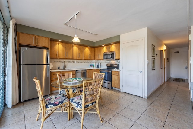 kitchen featuring appliances with stainless steel finishes, sink, light tile patterned floors, and hanging light fixtures