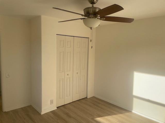 unfurnished bedroom with ceiling fan, a closet, wood finished floors, and baseboards