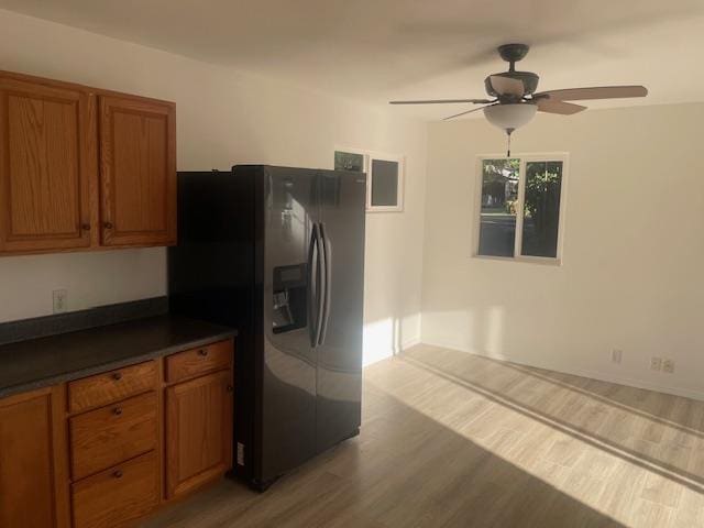 kitchen with light wood-style floors, dark countertops, brown cabinets, and fridge with ice dispenser