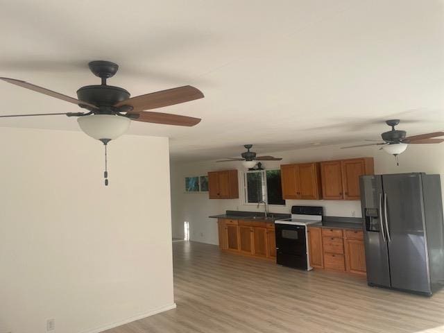 kitchen with electric range oven, dark countertops, brown cabinets, black refrigerator with ice dispenser, and light wood-style floors