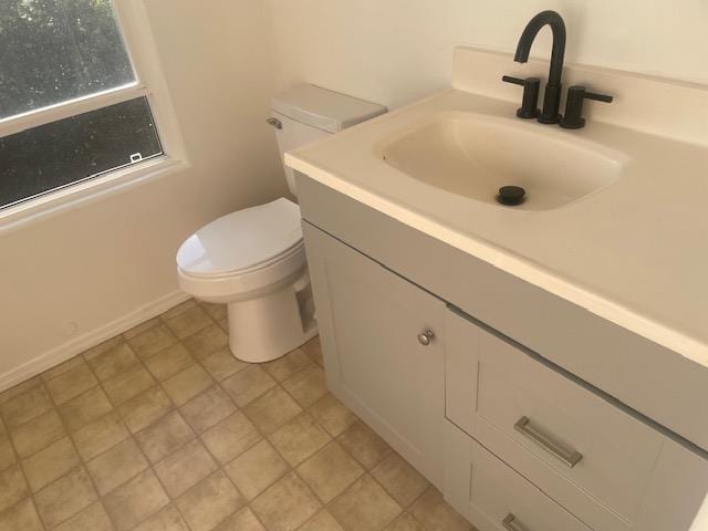 bathroom featuring vanity, toilet, and baseboards