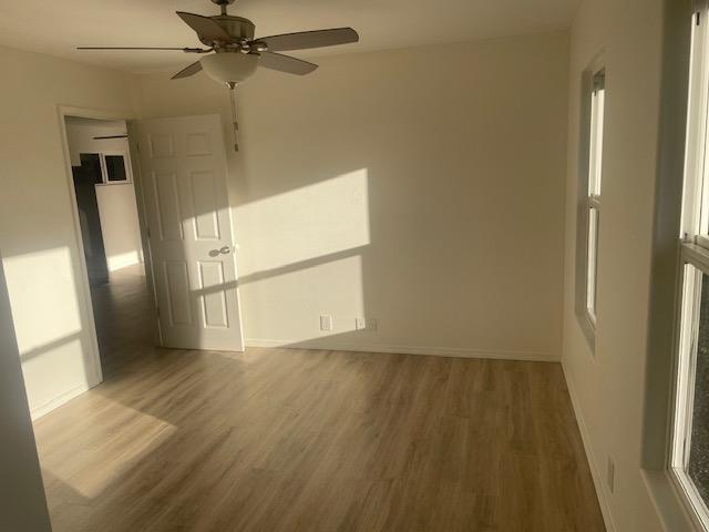 empty room with a ceiling fan, baseboards, and wood finished floors