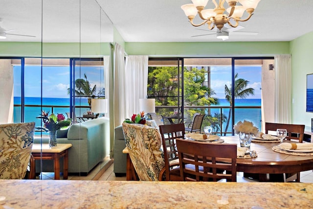 dining area featuring ceiling fan with notable chandelier, a water view, light tile patterned floors, and a textured ceiling