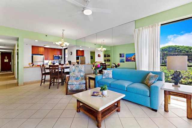 tiled living room featuring a textured ceiling and ceiling fan with notable chandelier