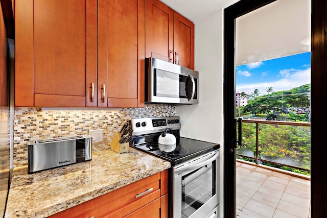 kitchen featuring decorative backsplash, light stone countertops, stainless steel appliances, and light tile patterned floors