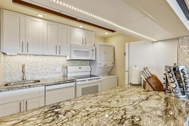 2385 S Kihei Rd Unit 306, Kihei, HI 96753 - kitchen featuring white appliances, stacked washer and clothes dryer, a sink, white cabinetry, and tasteful backsplash