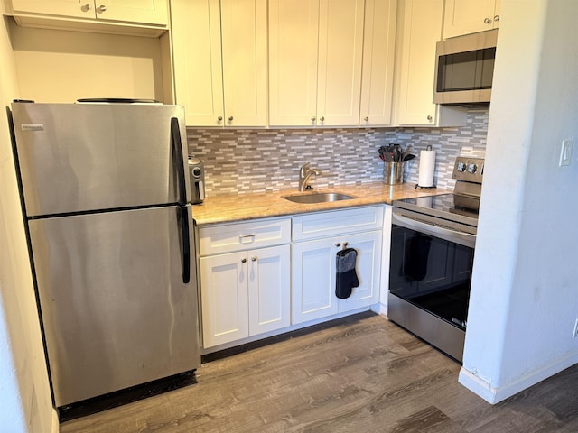 3660 Lower Honoapiilani Rd Unit 111, Lahaina, HI 96761 - kitchen with stainless steel appliances, a sink, wood finished floors, tasteful backsplash, and white cabinets