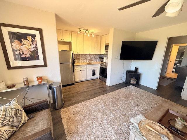 3660 Lower Honoapiilani Rd Unit 111, Lahaina, HI 96761 - living room with dark wood-type flooring, a wood stove, and a ceiling fan