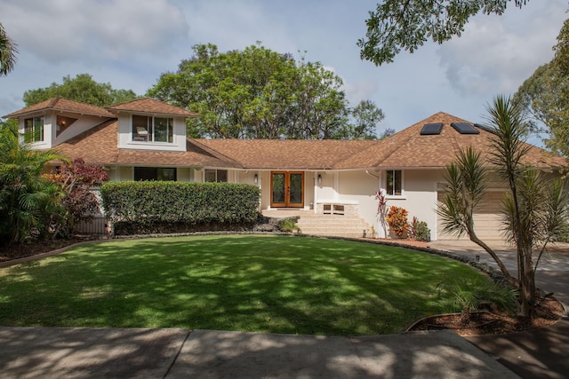 view of front of property with a front lawn, stucco siding, french doors, concrete driveway, and an attached garage