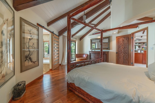 bedroom featuring vaulted ceiling with beams, a barn door, and hardwood / wood-style floors