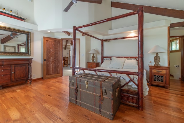 bedroom with high vaulted ceiling and wood finished floors
