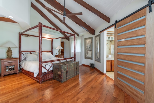 bedroom featuring baseboards, a barn door, vaulted ceiling with beams, and light wood finished floors