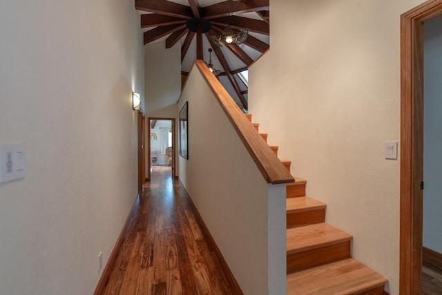 interior space with baseboards, ceiling fan, wood finished floors, and a towering ceiling