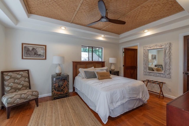 bedroom featuring baseboards, a raised ceiling, ceiling fan, and wood finished floors
