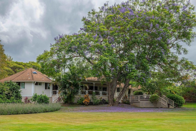 back of property with a porch, a yard, and stairway