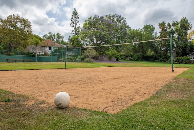 surrounding community featuring volleyball court, fence, and a lawn