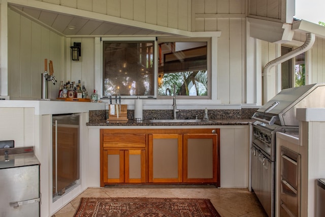bar featuring a sink, a bar, light tile patterned flooring, and wine cooler