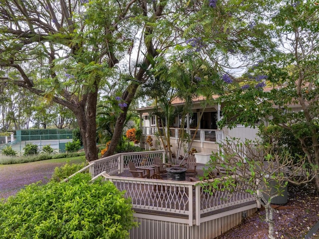 exterior space featuring a fire pit, fence, and a wooden deck