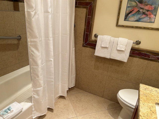 full bathroom with tile patterned floors, toilet, shower / tub combo with curtain, vanity, and tile walls