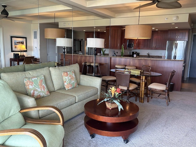 carpeted living room with beam ceiling, ceiling fan, and sink