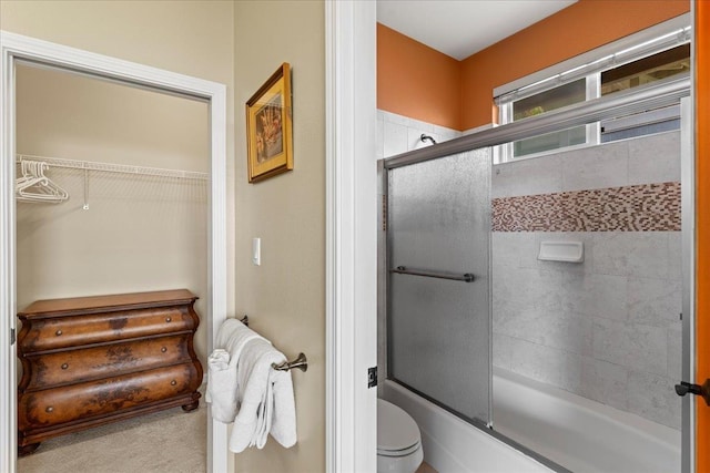 full bathroom featuring enclosed tub / shower combo, a walk in closet, and toilet