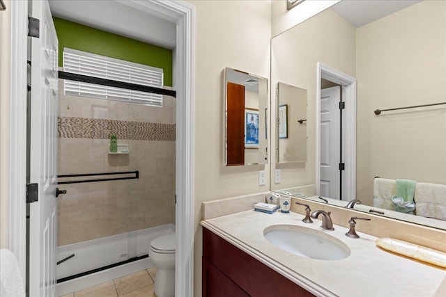 bathroom featuring tile patterned flooring, a stall shower, toilet, and vanity