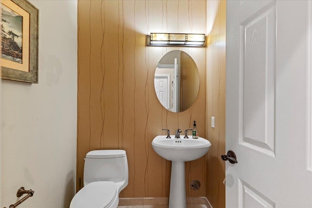 bathroom featuring wood walls and toilet