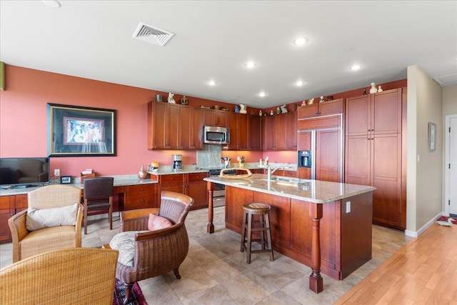kitchen featuring a sink, stainless steel appliances, recessed lighting, a kitchen bar, and visible vents