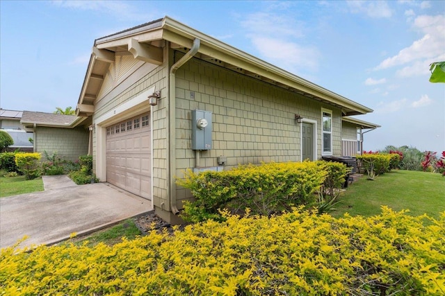 view of side of home featuring a garage, a yard, and driveway