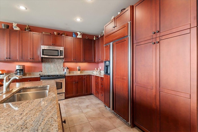 kitchen featuring recessed lighting, a sink, appliances with stainless steel finishes, and light stone countertops
