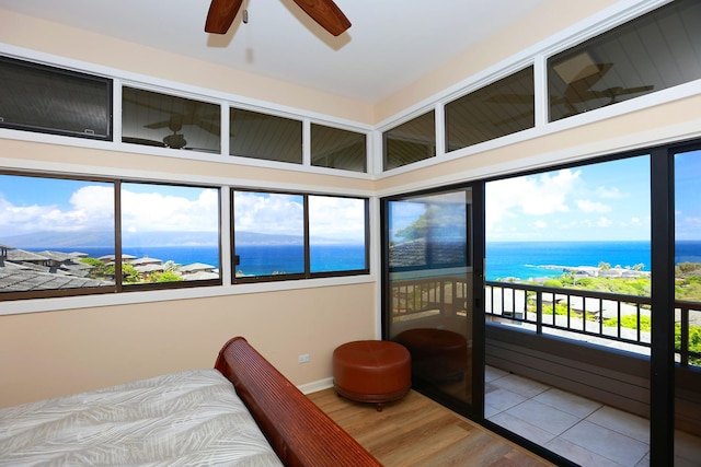 bedroom featuring multiple windows, a water view, and wood finished floors