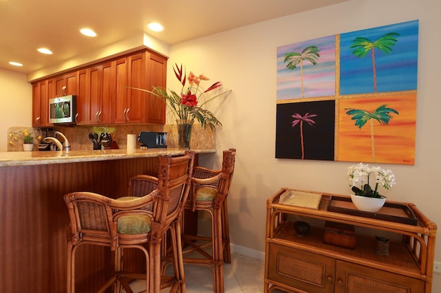 bar featuring light tile patterned flooring, recessed lighting, a sink, backsplash, and stainless steel microwave