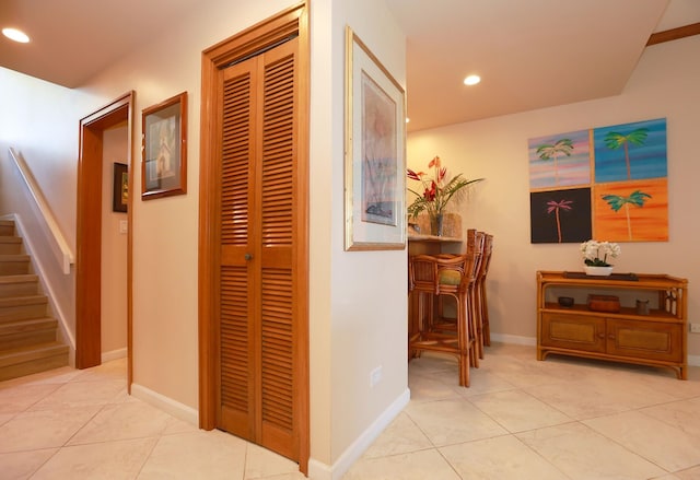 hallway featuring recessed lighting, light tile patterned floors, baseboards, and stairs