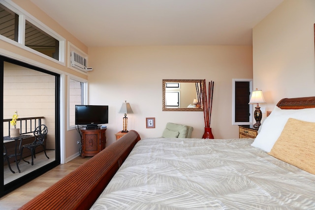 bedroom with access to exterior, a wall mounted AC, and wood finished floors