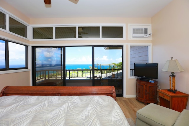 bedroom featuring access to outside, a wall unit AC, and light wood-style flooring