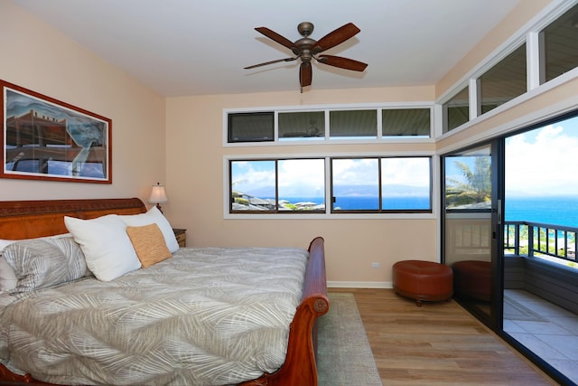 bedroom with access to outside, a water view, baseboards, and wood finished floors