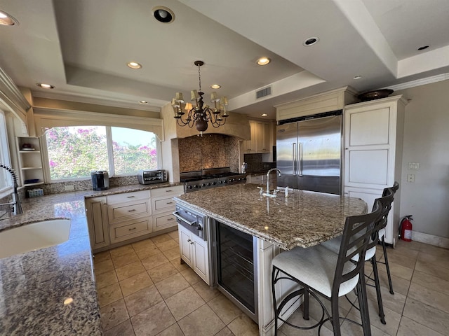 kitchen featuring a sink, a tray ceiling, visible vents, and built in fridge