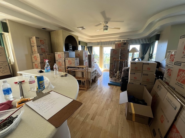 interior space with visible vents, ceiling fan, a tray ceiling, light wood-style floors, and access to outside