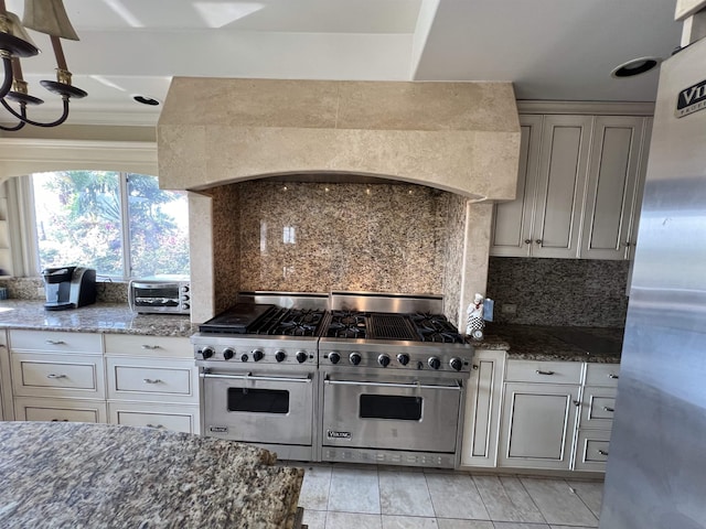 kitchen featuring stainless steel appliances, dark stone counters, a toaster, decorative backsplash, and custom exhaust hood