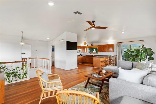 living room with ceiling fan, sink, vaulted ceiling, and hardwood / wood-style flooring