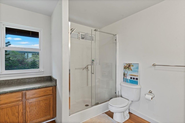 bathroom featuring wood-type flooring, toilet, and a shower with shower door