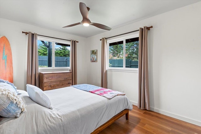 bedroom with hardwood / wood-style floors, ceiling fan, and multiple windows