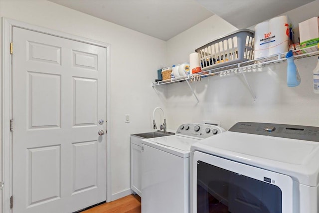 laundry area featuring cabinets, light wood-type flooring, independent washer and dryer, and sink