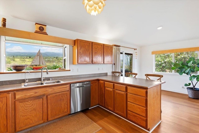 kitchen featuring dishwasher, kitchen peninsula, light hardwood / wood-style flooring, and a healthy amount of sunlight