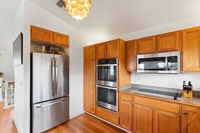 kitchen with light hardwood / wood-style floors, lofted ceiling, and appliances with stainless steel finishes